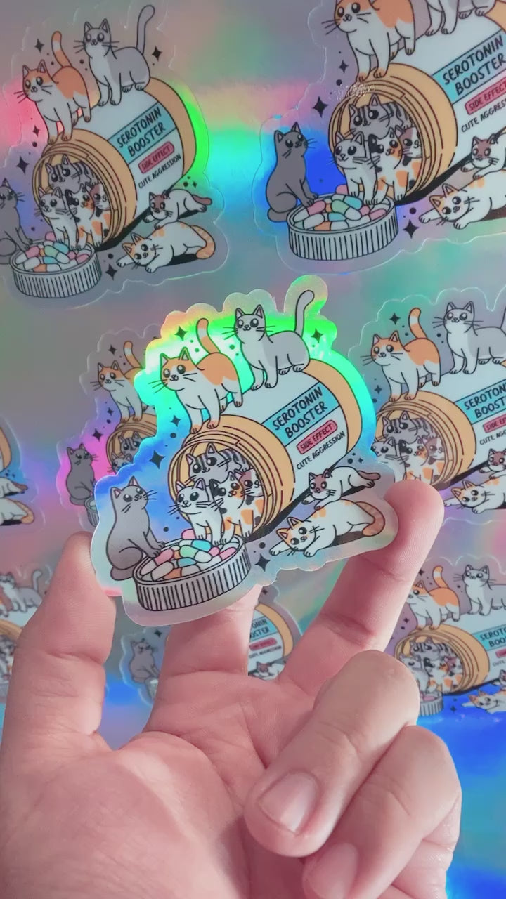 Load video: Custom holographic sticker featuring cute kitties. The sticker showcases a vibrant, multi-color holographic effect that changes with light, making the adorable cat designs stand out with a shimmering, eye-catching appeal. Perfect for decorating laptops, notebooks, or any personal items.